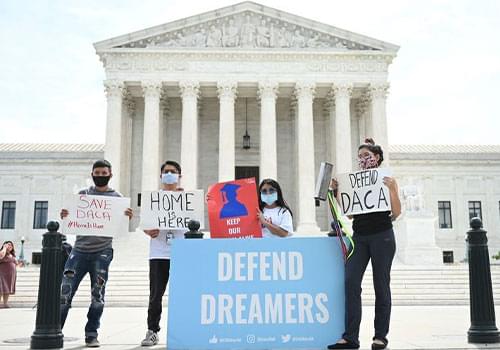 Student standing outside Supreme Court in Washington with DACA Signs