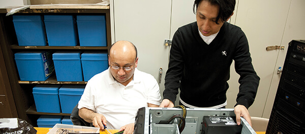 Student and Faculty working on fixing a computer together