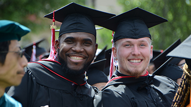 two students with cap-and-gowns at commencement